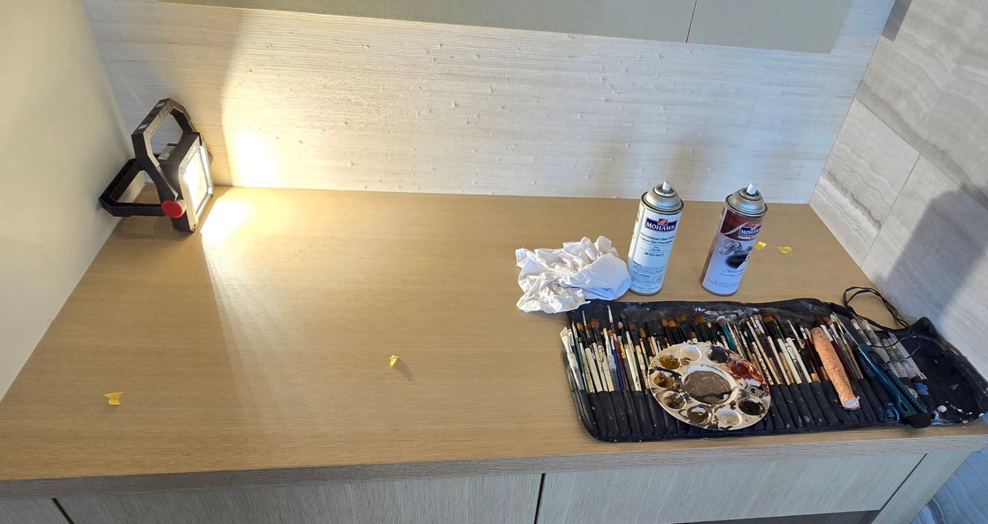 On-site work bench with artist brushes, palette, and clear coat cans used for color matching